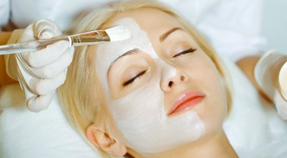 Applying face mask with brush on woman's face