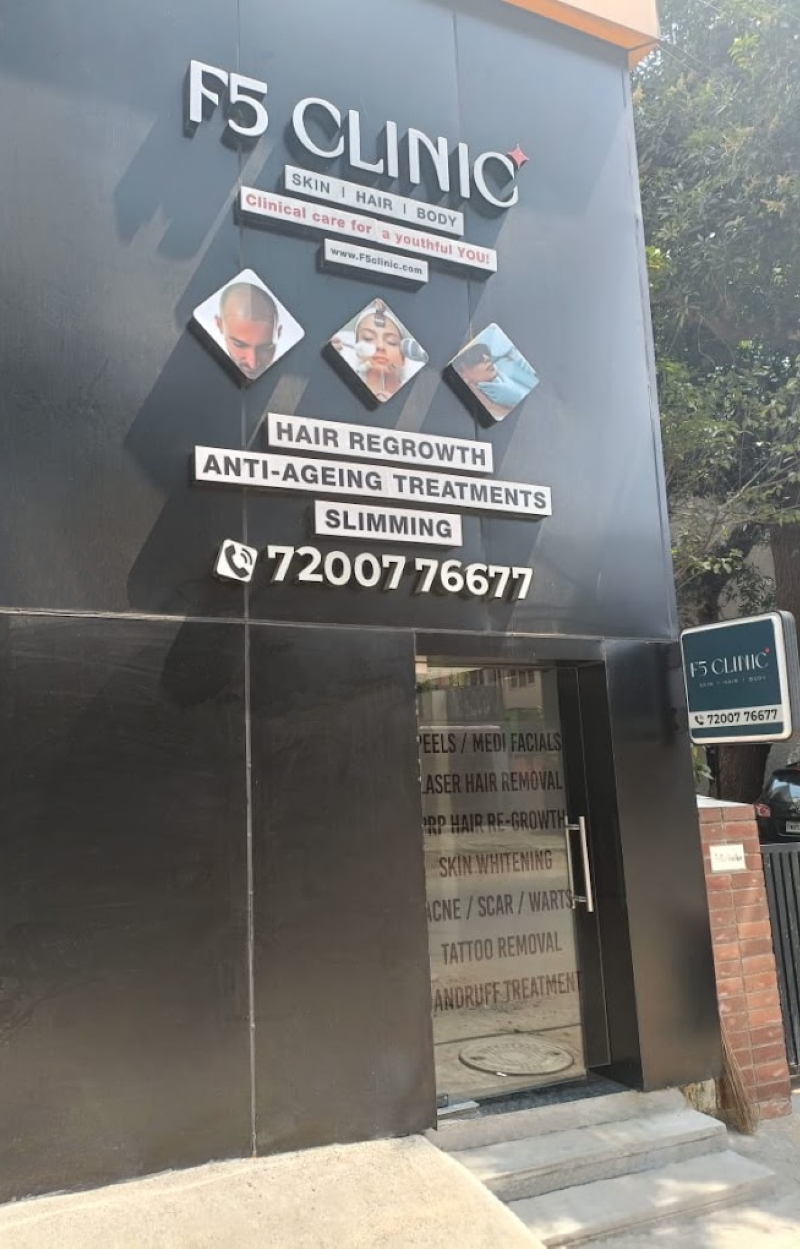 Wall in neon sign that says 'F5 Clinic' with vase of flowers