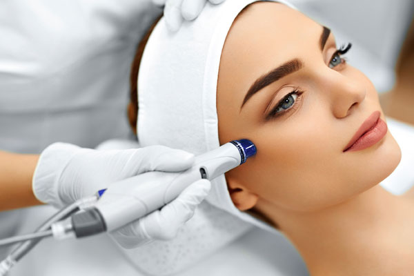 Woman in white headband at clinic receiving hydrafacial treatment